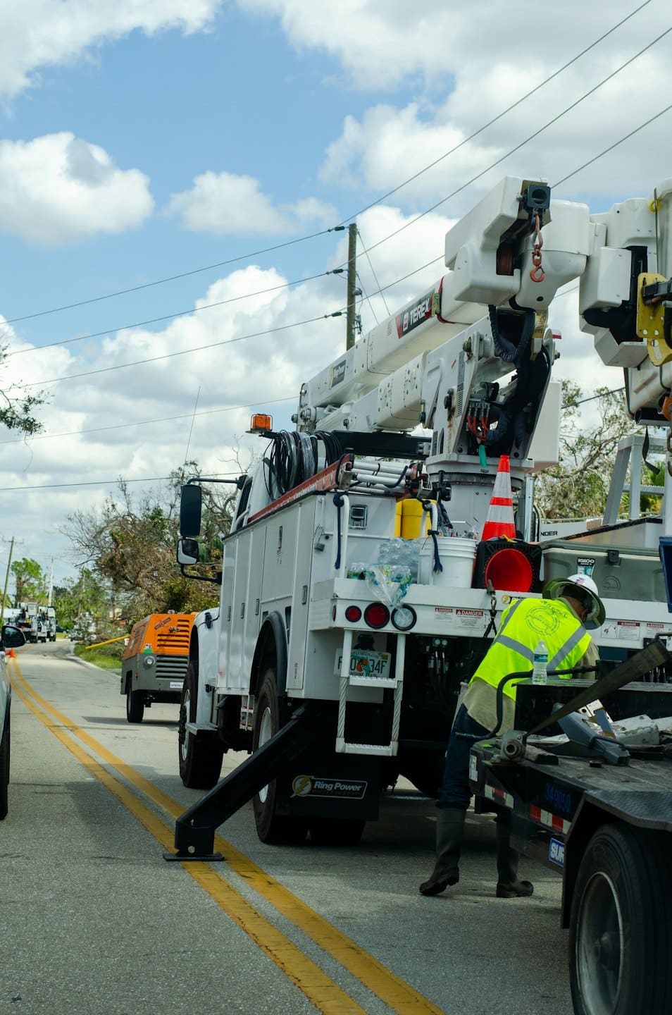 Technician in yellow vest works on utility truck lift.